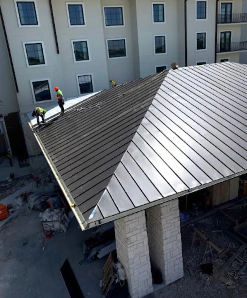 Crew installing standing seam metal roof panels on a commercial project in La Porte